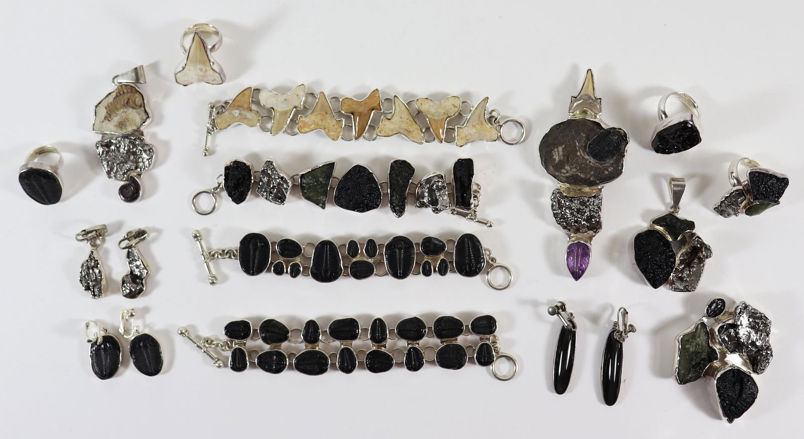 CHARLES ALBERT STERLING MOLDAVITE FOSSIL JEWELRY: A collection of Charles Albert jewelry to include (4) bracelets including a shark tooth bracelet, (4) pendants, (4) rings and (3) pairs of earrings. Charles Albert jewelry is made of natural stones an