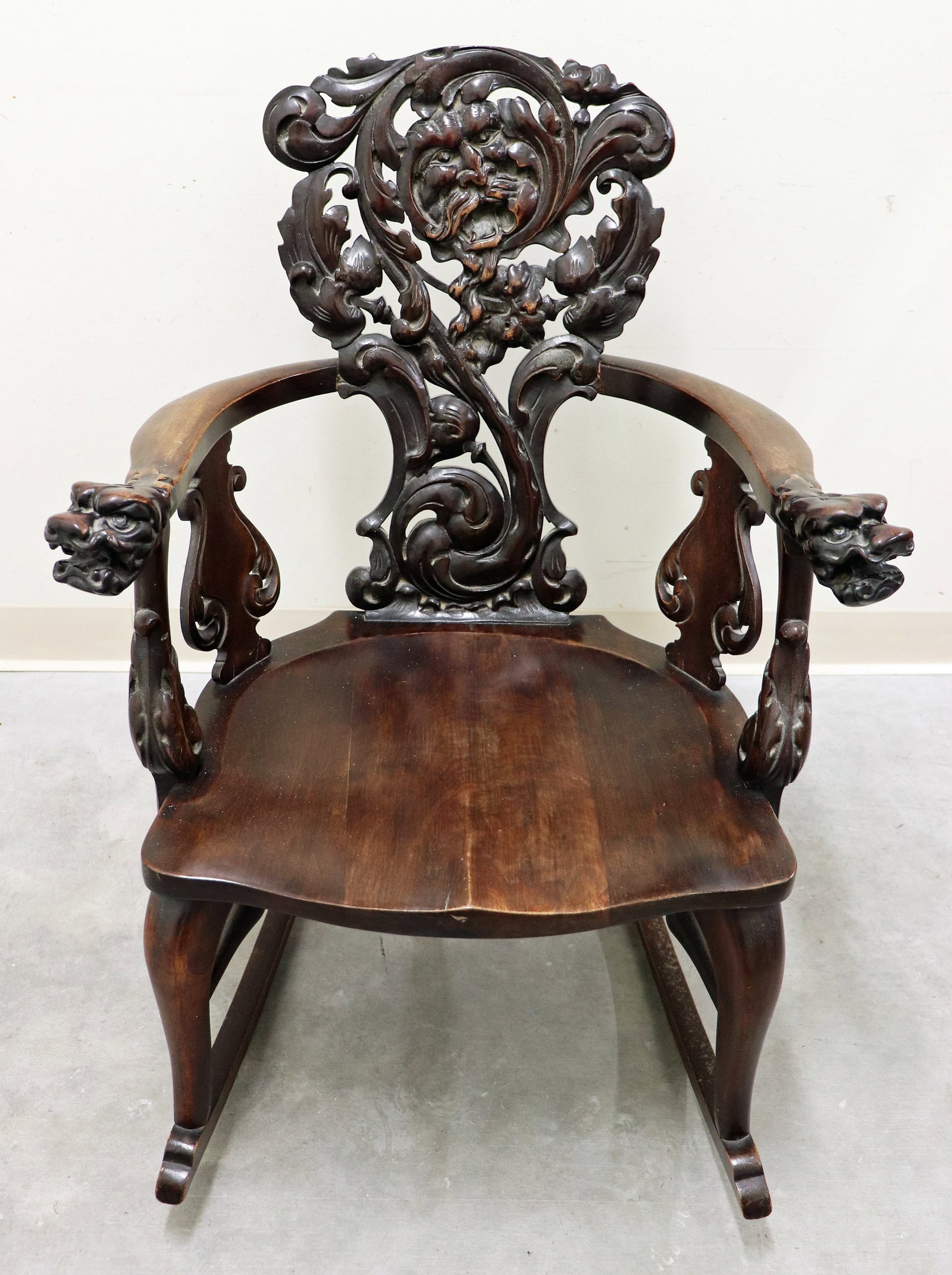 RENNAISANCE REVIVAL ATT'B RJ HORNER ROCKING CHAIR: An antique gothic carved mahogany rocking chair with lion head arms, and figural heads. Measures 25"W x 35" H x 31"D