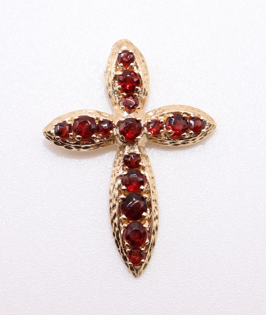 14K YELLOW GOLD GARNET CROSS: 14K yellow gold cross with a total of 15 round garnets set in the center. It measures 1" long. Weight 2.1 g.