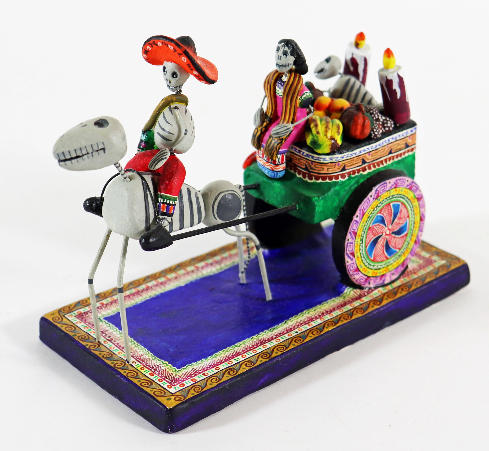 SAUL MONTESINOS DAY OF THE DEAD SCULPTURE: Saul Montesinos Mexican Day of the Dead clay sculpture of a skeleton man on horseback with woman and dog in a cart full of produce and candles. Signed on side. Measures 6.25" long 4.75" tall.