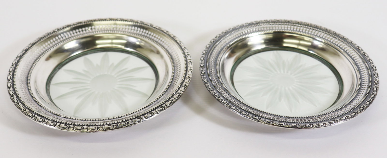 (2) FRANK WHITING STERLING WINE COASTERS: A pair of Frank M. Whiting sterling silver rimmed wine bottle coasters/ trivets with etched glass floral pattern, "Talisman Rose", measures 6 1/2" x 3 3/4".