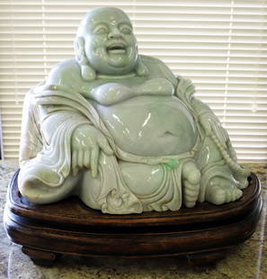 MONUMENTAL CHINESE JADE "LAUGHING BUDDHA" STATUE: Large Chinese Laughing Buddha statue. Carved light green Jade, the Buddha is in a sitting position on an oval wood (teak?) base with four feet. Represents happiness, prosperity and good luck. He is qu