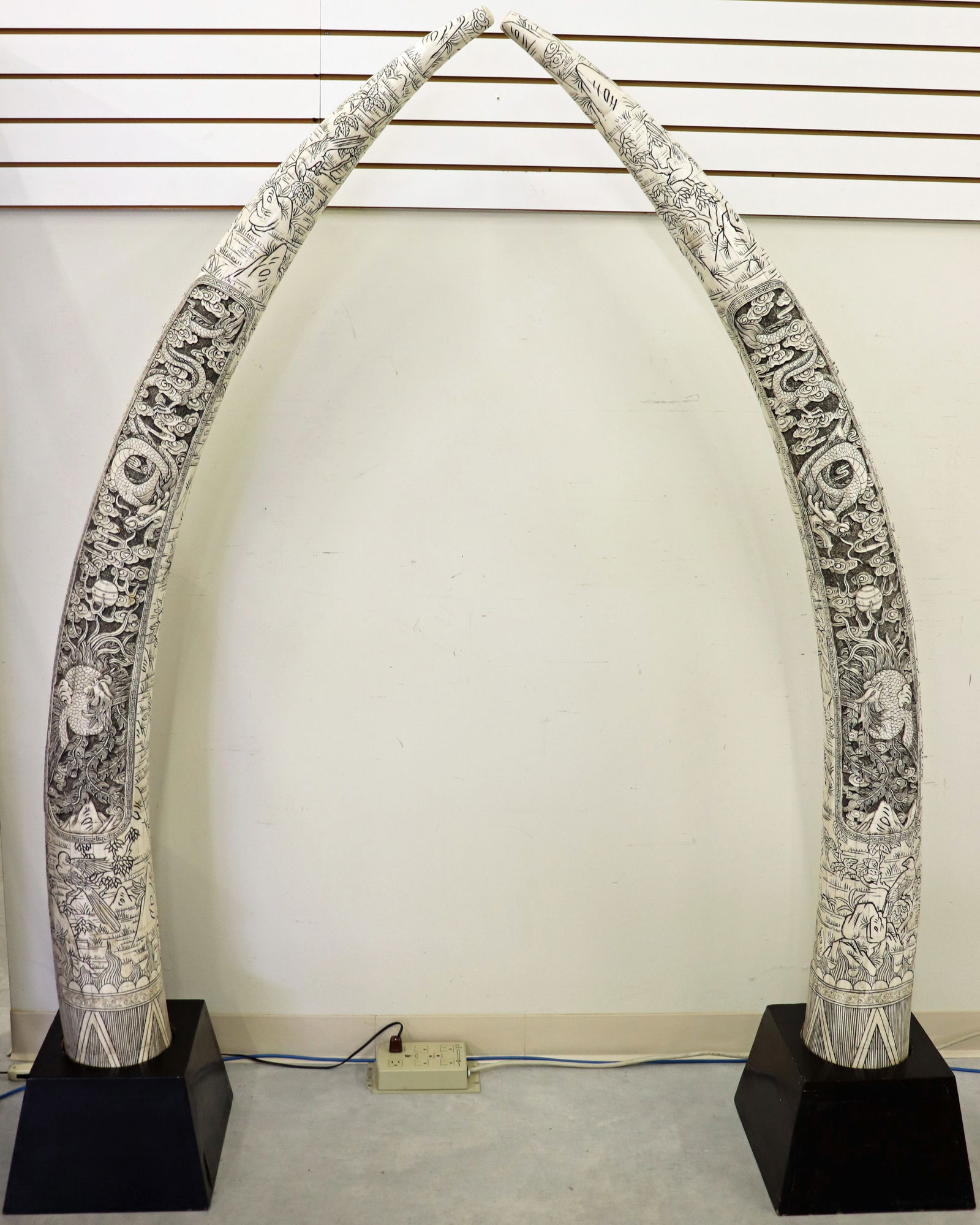 (2) CHINESE MONUMENTAL CARVED BONE TUSKS: A pair of Chinese relief bone tile tusks, on a square shaped base. Carvings depicting nature scenes with birds, flowers, trees and dragons. Measures 78" tall, wooden base is 13 1/2 " x 9".