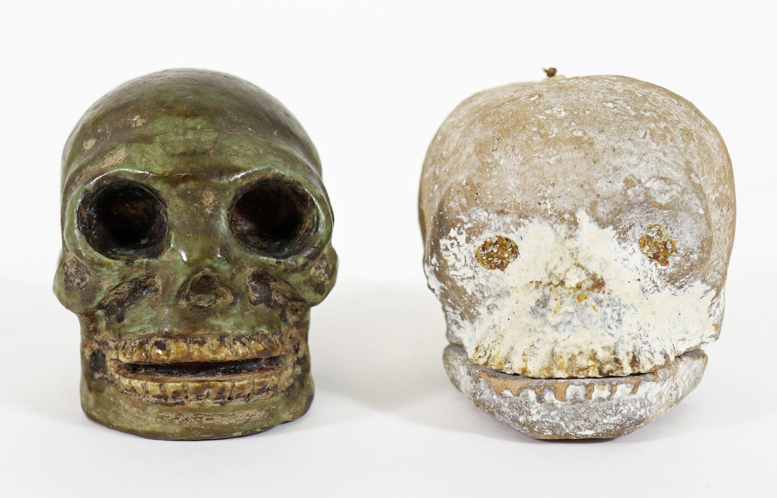 (2) MORI SKELETON SKULL SCULPTURES TALKING HEAD: A clay skeleton head with a string that when pulled, opens and closes his mouth. Also included is a green lightweight stone type material with deep set eye sockets and teeth. Approx 3" x 2 1/2"