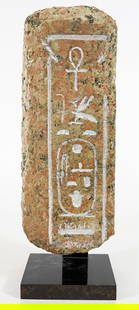 EGYPTIAN GRANITE FAIENCE HANDLE WITH HIEROGLYPHICS: An Egyptian stone fragment with hieroglyphics mounted on a stand. The handle measures 12 1/2" x 5" x 3" (Mounted 14 1/2" x 5" x 4"). From the Andrew Cunningham Ware Estate.