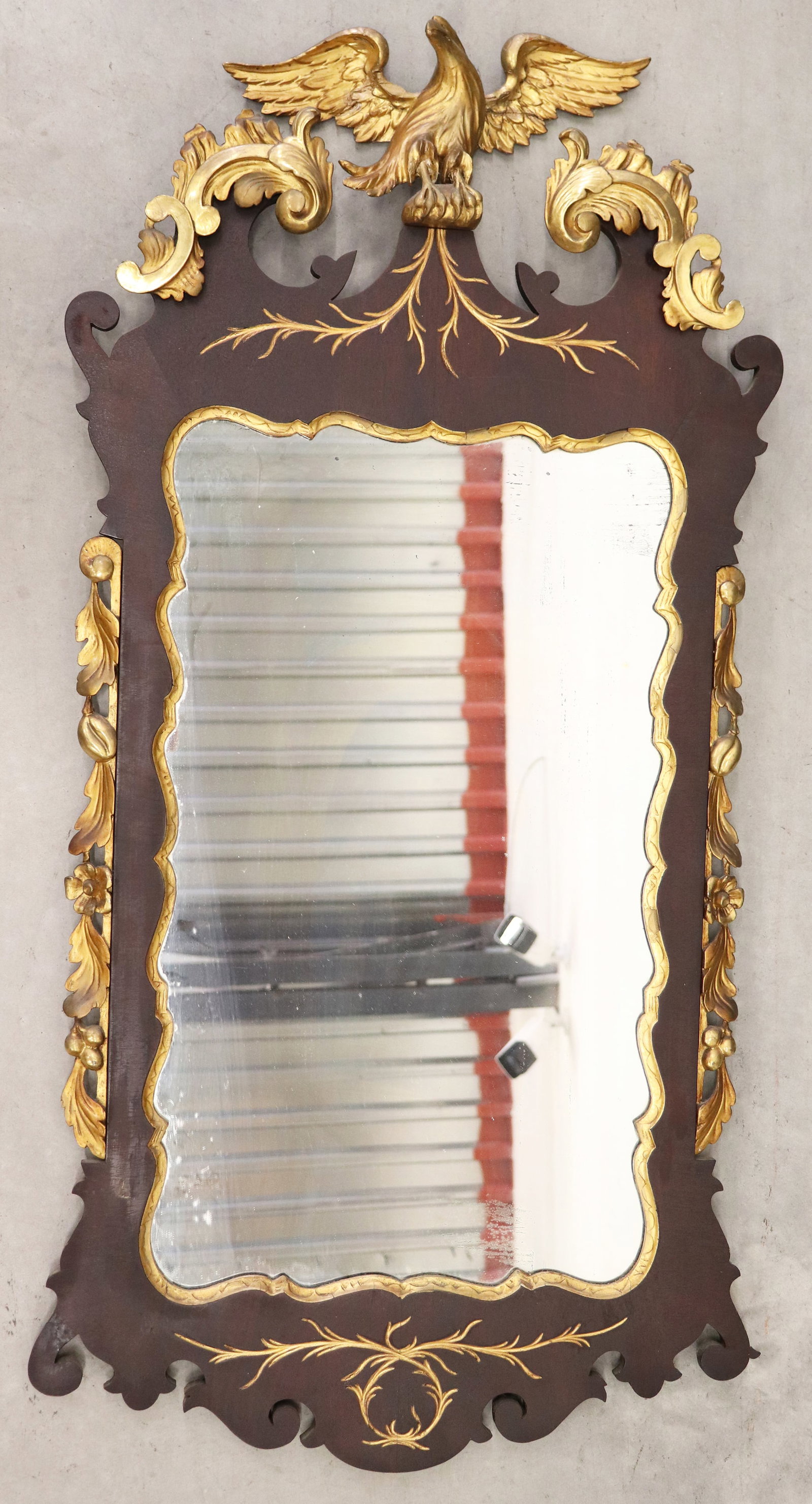 GEORGE III STYLE PARCEL GILT MAHOGANY MIRROR: A George II style mahogany mirror with a carved giltwood eagle / phoenix (needs to be repaired) with applied gilt foliate scrolls. Measures 46" x 22" x 3.5"