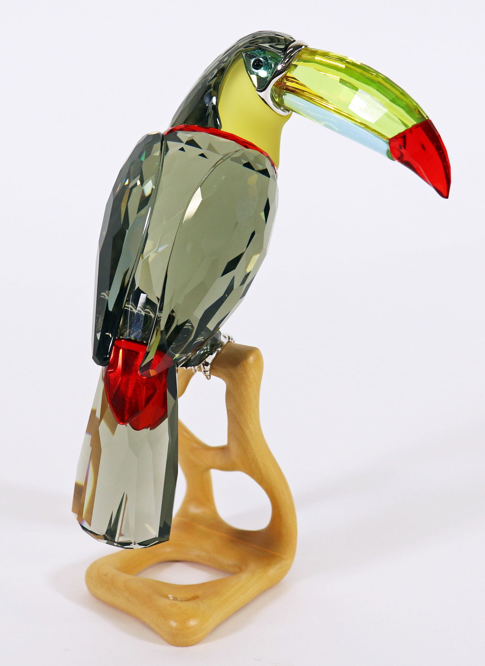 SWAROVSKI CRYSTAL TOUCAN BLACK DIAMOND FIGURINE: A Swarovski crystal Toucan, with black diamond crystal and chrome accents, talons, multi colored crystal bill, perched on a wood stand . From the Paradise Birds collection. Model #0850600. Measures 8"
