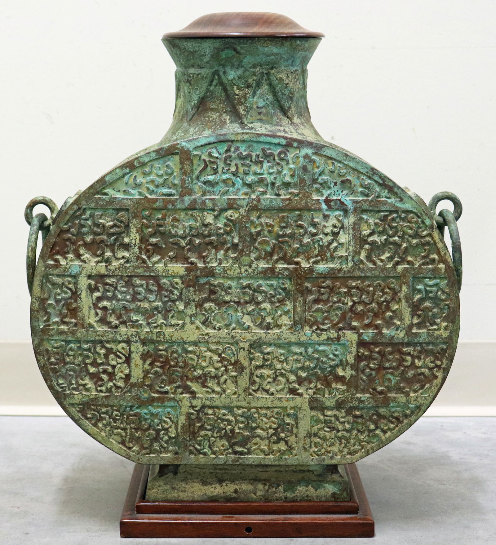 CHINESE BRONZE PATINATED MOON VASE: Unique Chinese bronze bianhu vase with side handle rings, comes with a wood base and wood lid cover, style likely inspired by ancient ritual wine vessels of the Eastern Zhou dynasty, vase measures 18"