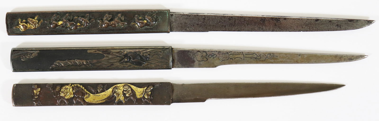 (3) JAPANESE KOZUKA KNIVES: Collection of (3) Japanese Kozuka knives. Two signed on blades. Handles depict horses, bird and waves, and figures with a dragon puppet. 7 7/8" to 8 3/4" long. From the Estate of Japanese collector