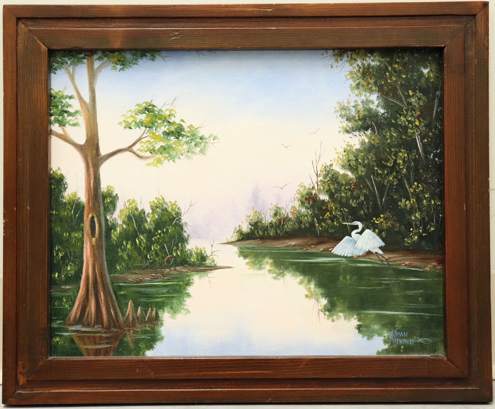 JOAN ARNOLD FLORIDA BACKWOODS RIVER PAINTING: Joan Arnold painting of a Florida backwoods river inlet scene with detailed green vegetation, birds, water, and tall cypress tree. Signed lower right. Measures 14" x 11" on canvas and 16.5" x 13.5" wi
