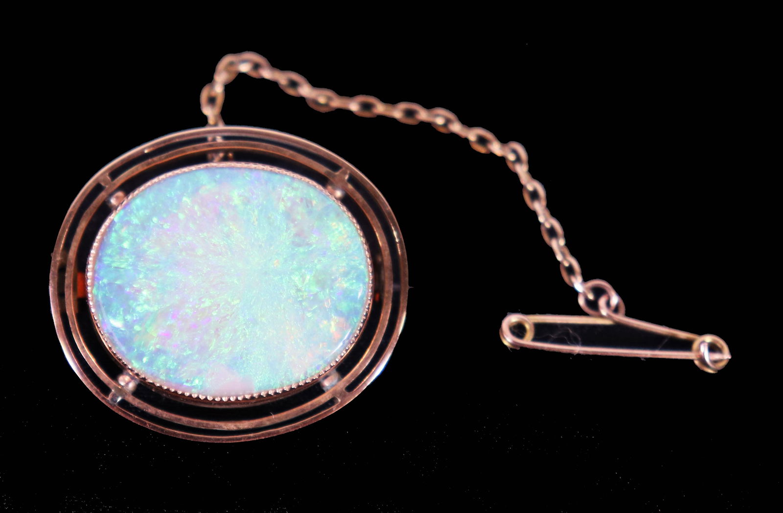 15K YELLOW GOLD 6.60 CARAT FIERY OPAL BROOCH: This vibrant colored opal pin is set in a 15 carat yellow gold frame with a safety chain. The cabochon opal measures 20.25 x 17.35 c 3.3mm. Weight 6.22 g. Purchased at Blooms Fine Jewelers in New