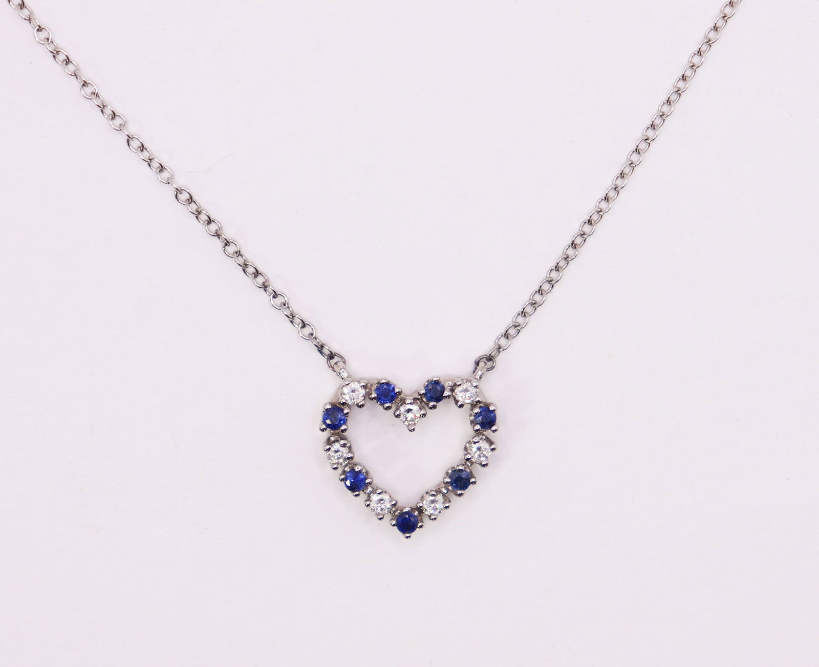 18K WHITE GOLD DIAMOND & SAPPHIRE HEART NECKLACE: A diamond and sapphire heart pendant set in 18K white gold with a 16" 18K white gold chain. 3.1 grams. Heart pendant approximately 1/2" wide.
