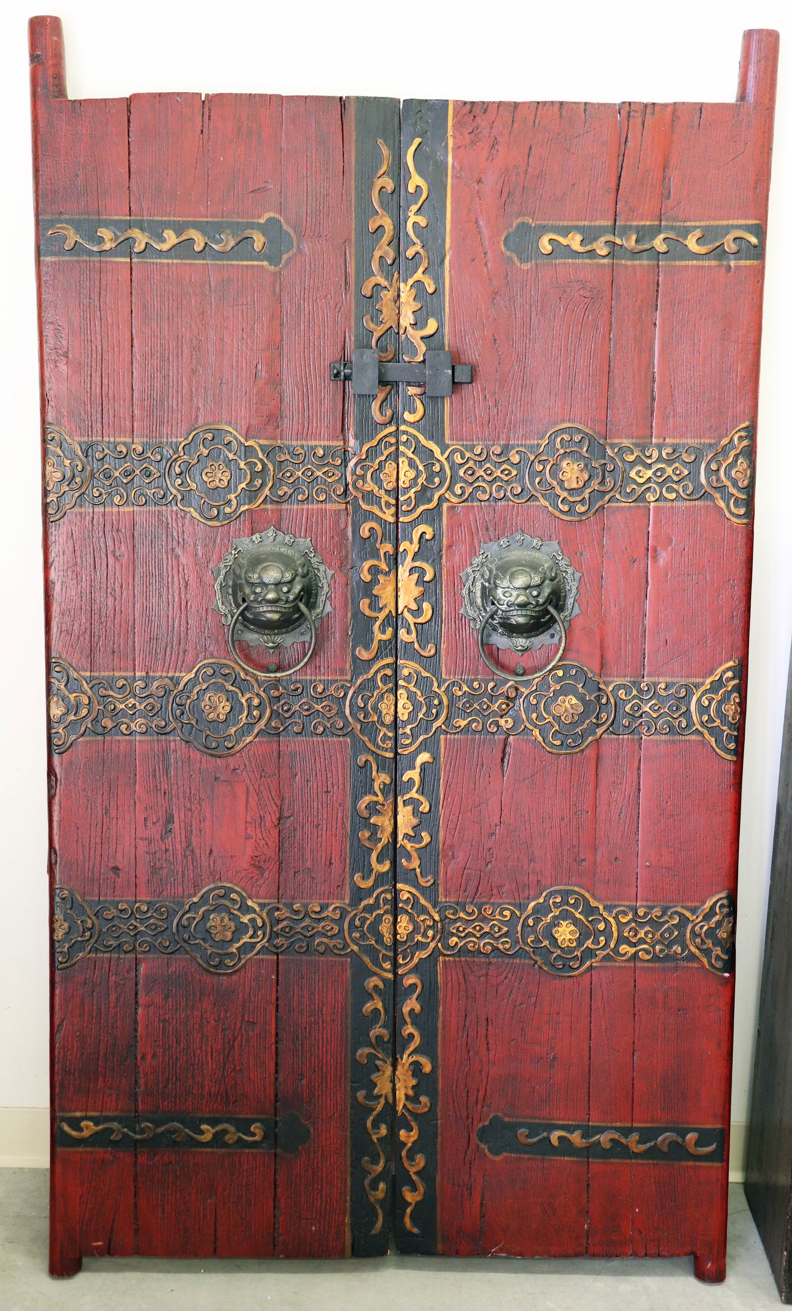 ARCHITECTURAL INDONESIAN HARDWOOD DOORS: A pair of architectural Indonesian hardwood courtyard or temple doors with metal foo lion ring pulls, sliding latch closure and black and gilt gold decorative designs. Overall the doors measure 71" wi