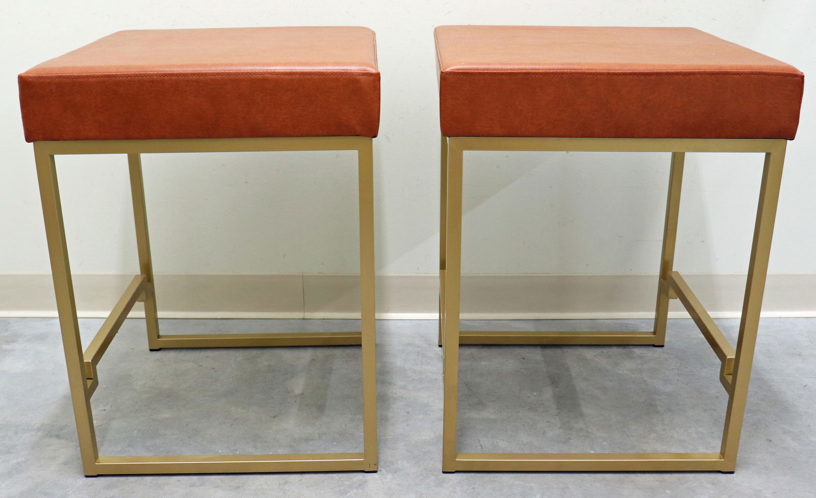 (2) COUNTER BAR STOOLS WITH METAL BASE: A pair of contemporary Modern counter stools with an upholstered seat and brass colored metal base with foot rests. They are from the Boice collection manufactured by Acme Furniture Company. Never use