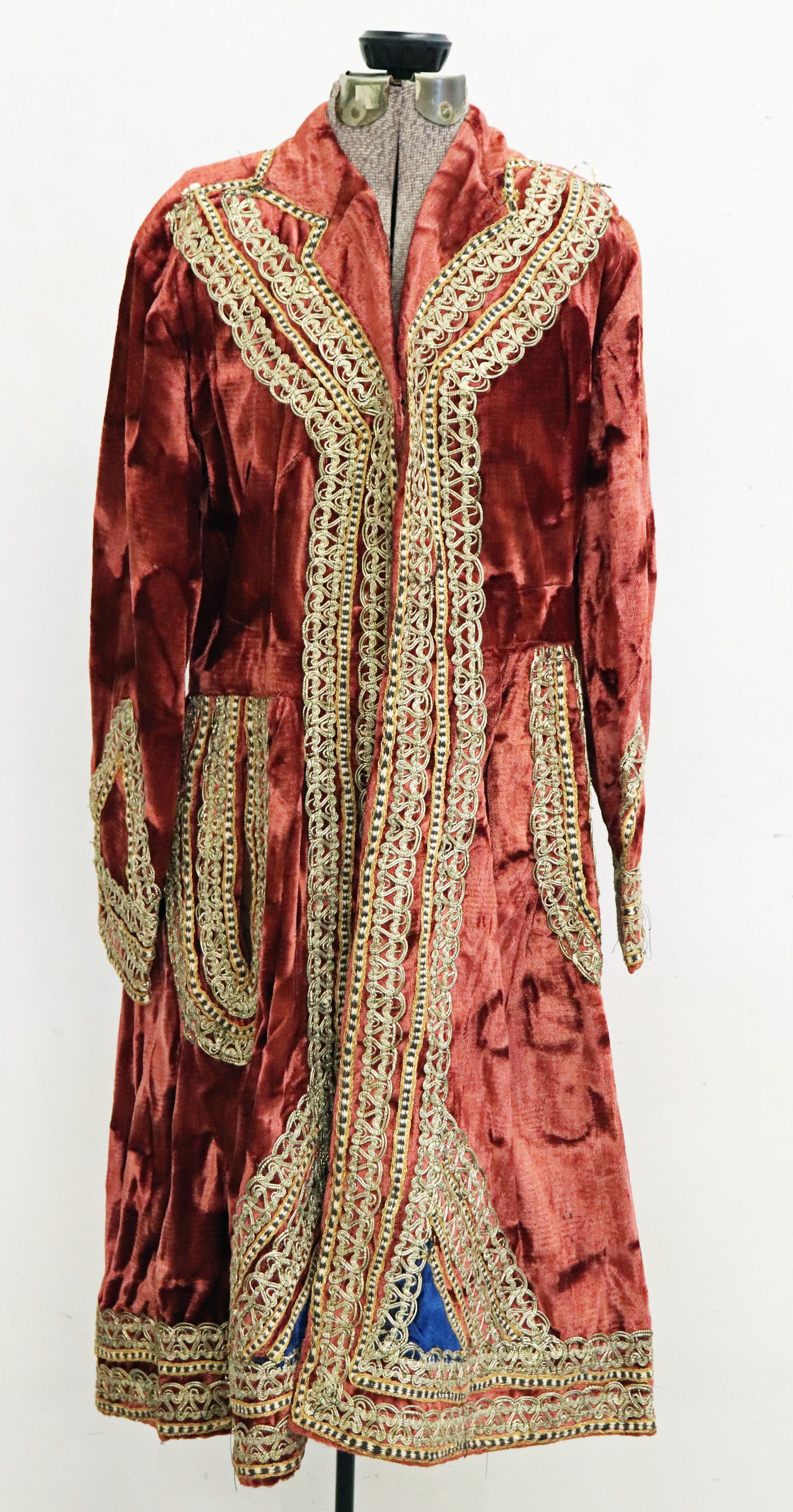 ANTIQUE PERSIAN SAFAVID ROBE: A lavish Persian robe with gold threads and long flowing sleeves. This textile has an embroidered trim and is a vibrant burgundy color with blue accents. Some age related wear. Measures 38" from