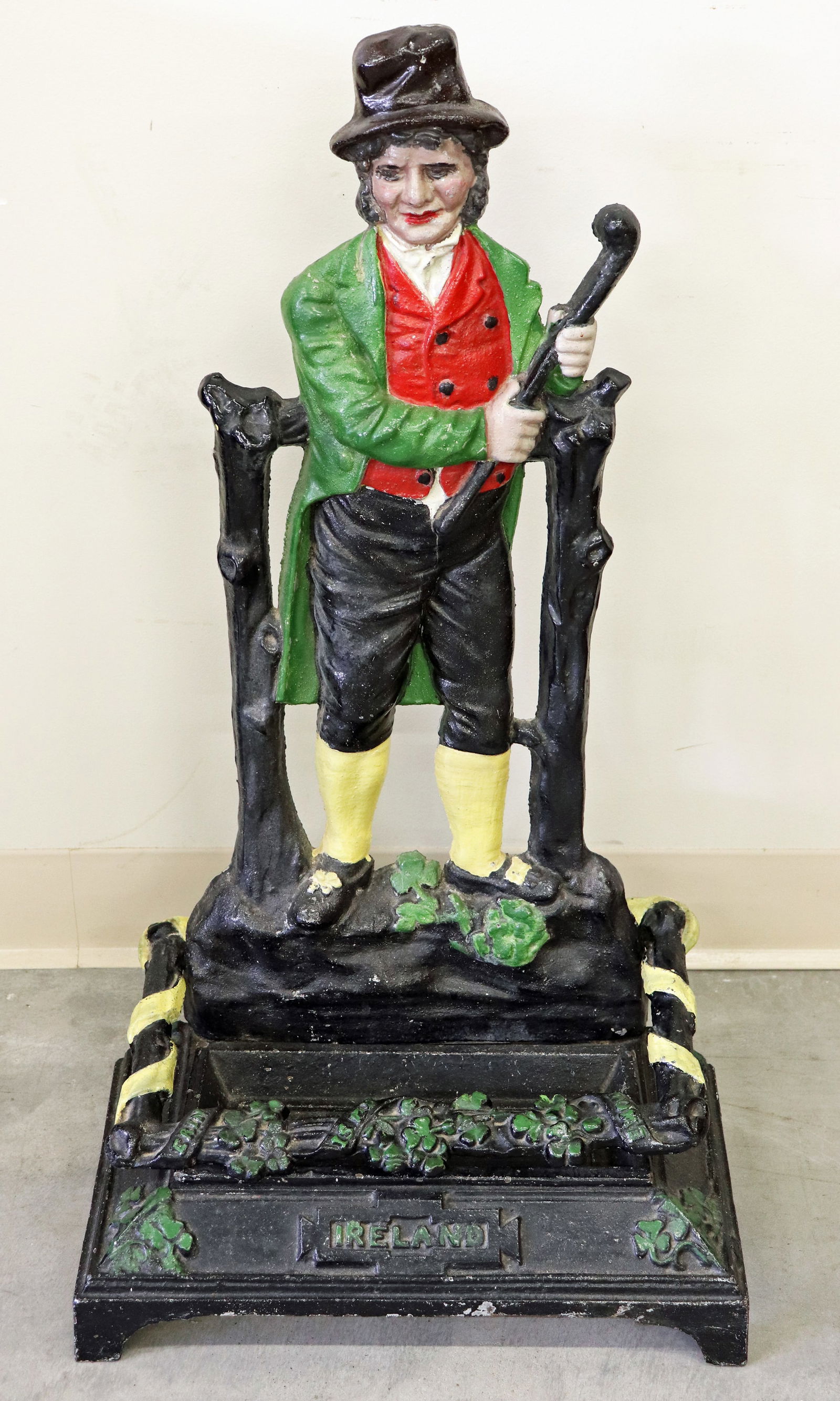 CAST IRON IRELAND UMBRELLA CANE STAND: Painted cast iron umbrella / cane stand with standing figure. Bottom with raised lettering Erin is my Home and Ireland. Top holder detached (screws in back to attach). Measures 29" tall 16" x 8" wide.