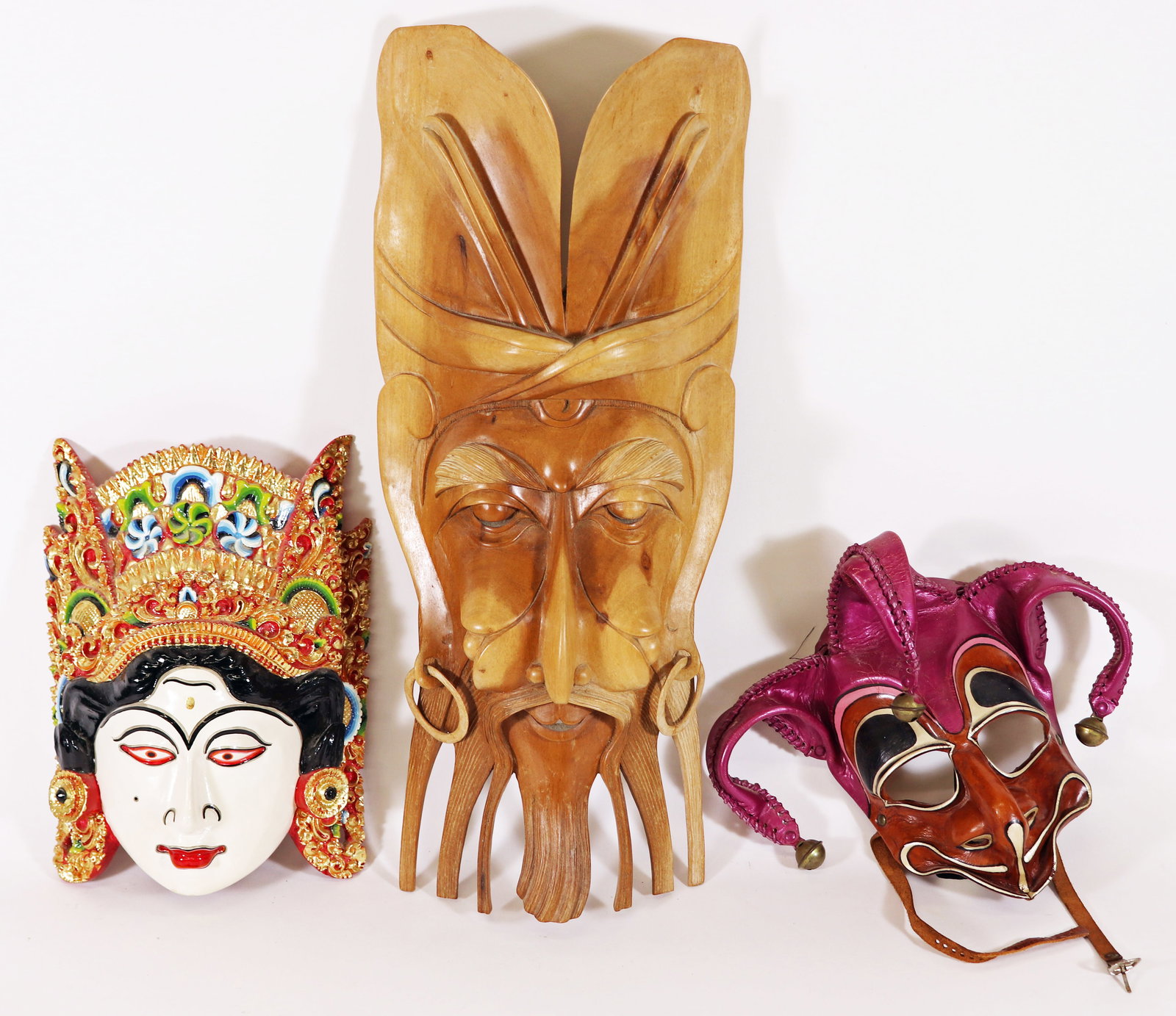 (3) ITALIAN, WOOD BALINESE, & LEGONG DANCE MASKS: A leather theatrical masquerade mask hand painted in purple, brown, black tones with leather straps and adorned with small bells. Dated 1983 and signed by Italian artist Fratelli de Marchi. Carved