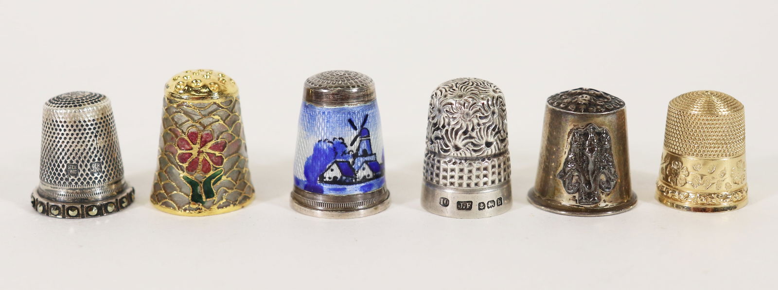 (6) ANTIQUE GOLD & STERLING THIMBLES: A collection of sewing thimbles to include a Simons Bros 14K gold thimble (3.9g), a Siam sterling thimble, a James Fenton & Co Birmingham sterling thimble, a Plique a Jour cloisonne thimble, a German
