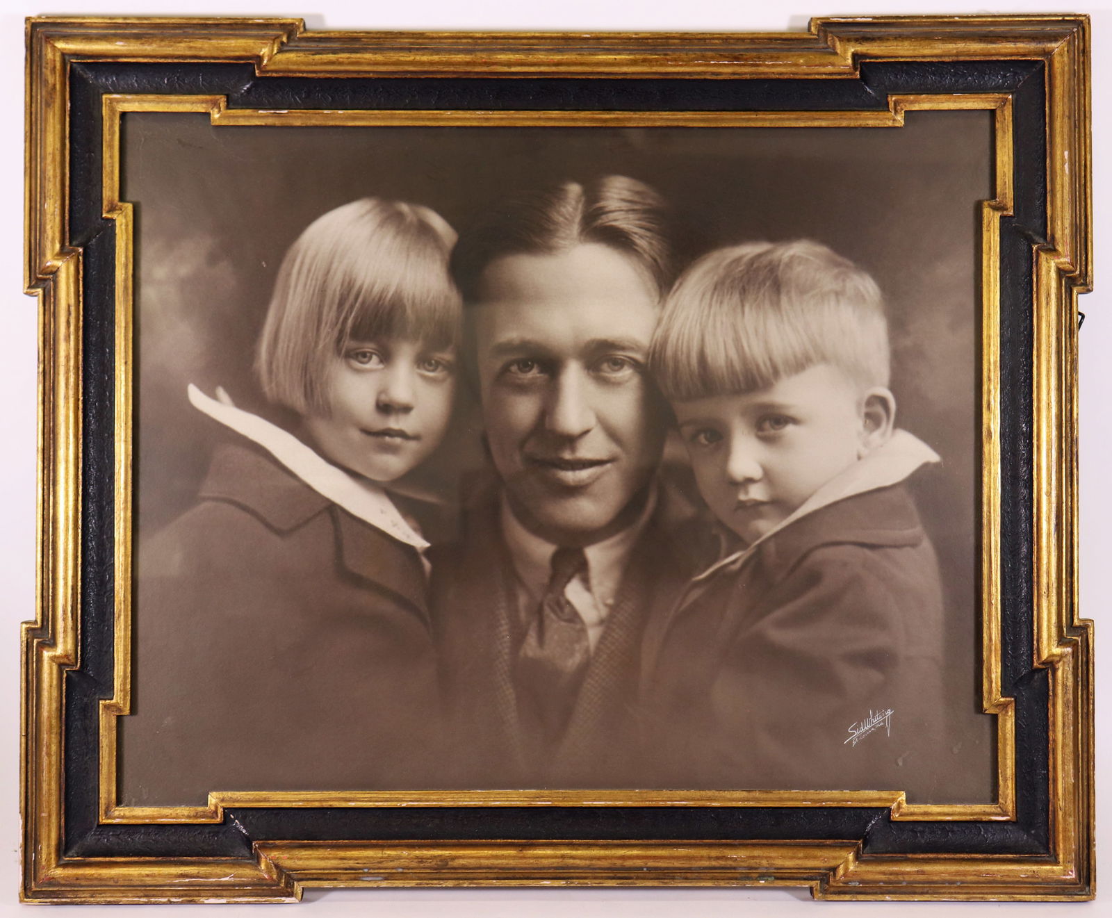 ANTIQUE SID WHITING BLACK & WHITE PHOTO: Antique framed black and white photo of a father with two children. Signed lower right Sid Whiting St. Louis Mo. Measures 29" x 24" in a square frame (some losses to edges).