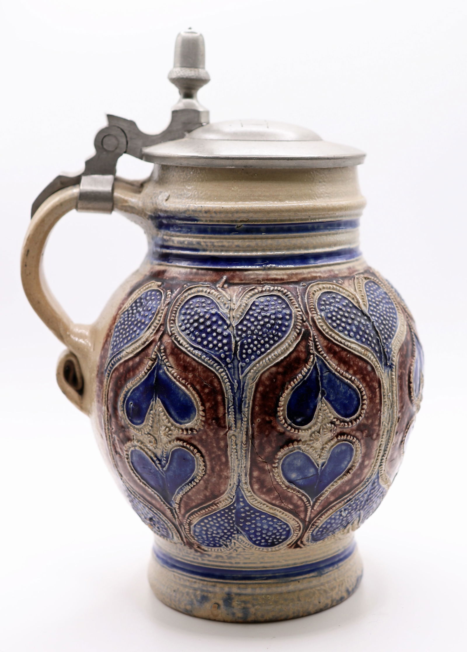 WESTERWALD SALT GLAZED GERMAN JUG: Antique German salt glazed tankard stein attributed to Westerwald. Blue heart pattern and pewter lid with lettering. Measures 4" tall 5" wide.