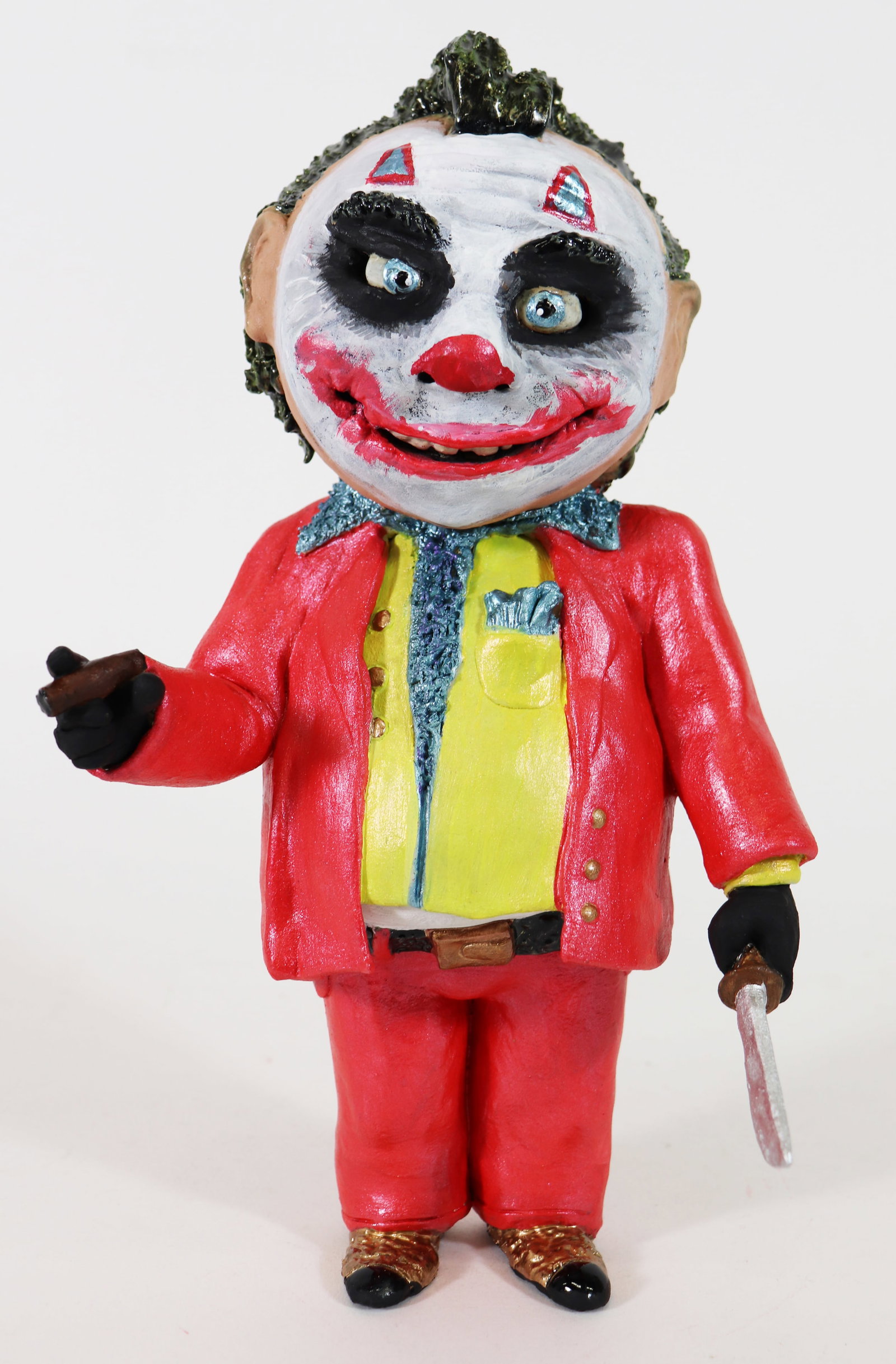 JEREMY WARDELL JOKER FOLK ART SCULPTURE: Jeremy Wardell Folk Art pottery sculpture of a joker holding a knife and a cigar. Modeled after Heath Ledger's Joker in The Dark Knight (2008). Measures 11.5" tall, 6" x 4.5" wide.