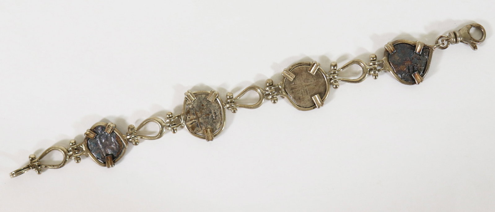 STERLING BRACELET WITH 17TH CENTURY 1/2 REAL COINS: Sterling silver bracelet with 17th century 1/2 real coins. Includes paperwork and original box from West Bay Trading Company. Bracelet measures approximately 7" and includes extra 1" link with coin.