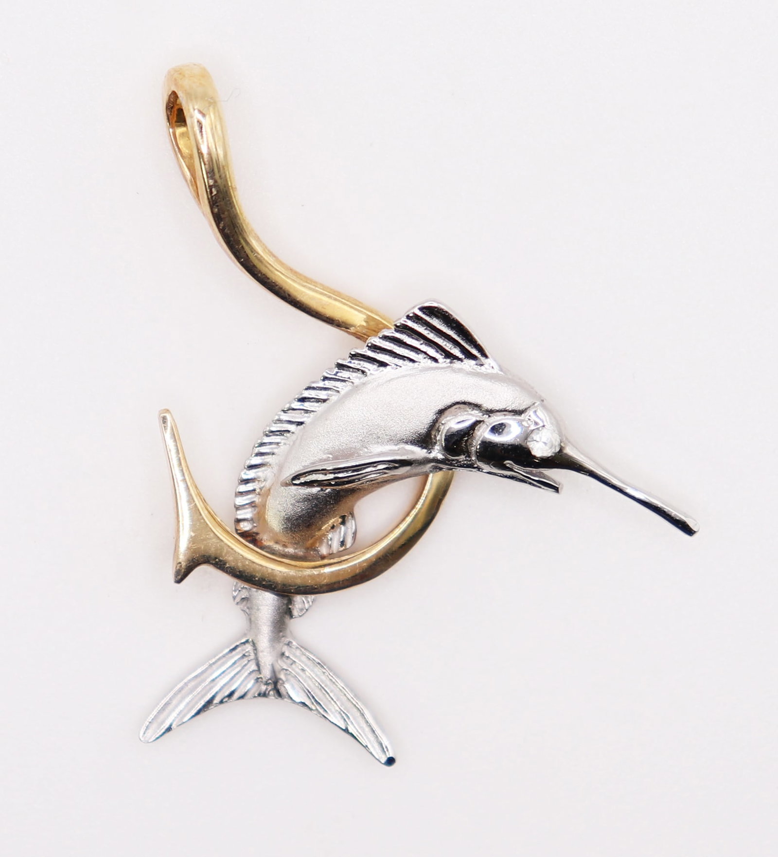 14K & SILVER TWO TONE MARLIN & HOOK PENDANT: Nautical two tone 14KT yellow gold and sterling silver pendant. Pendant features a silver marlin with 14KT yellow gold hook. Measures 1 3/8" long and weighs 4 grams.