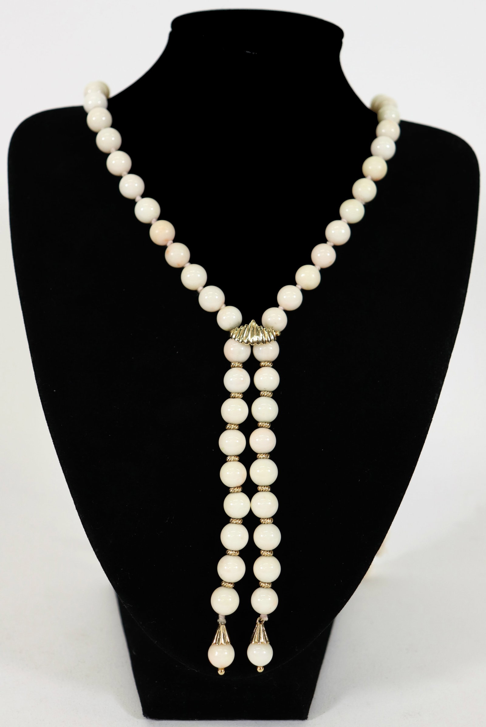 14K ANGEL SKIN CORAL LARIAT NECKLACE: A strand of angel skin coral beads with 14K yellow gold accents. The coral beads are 9mm and the necklace is 28" long with a 4.5" drop.