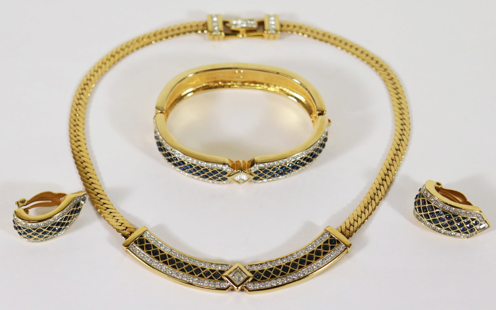 SWAROVSKI NECKLACE BRACELET & EARRINGS SET: A sparkling Swarovki crystal necklace set that include a gold plated curb link collar necklace with brilliant white crystals surrounded by faceted blue stone in a geometric pattern with a matching bra