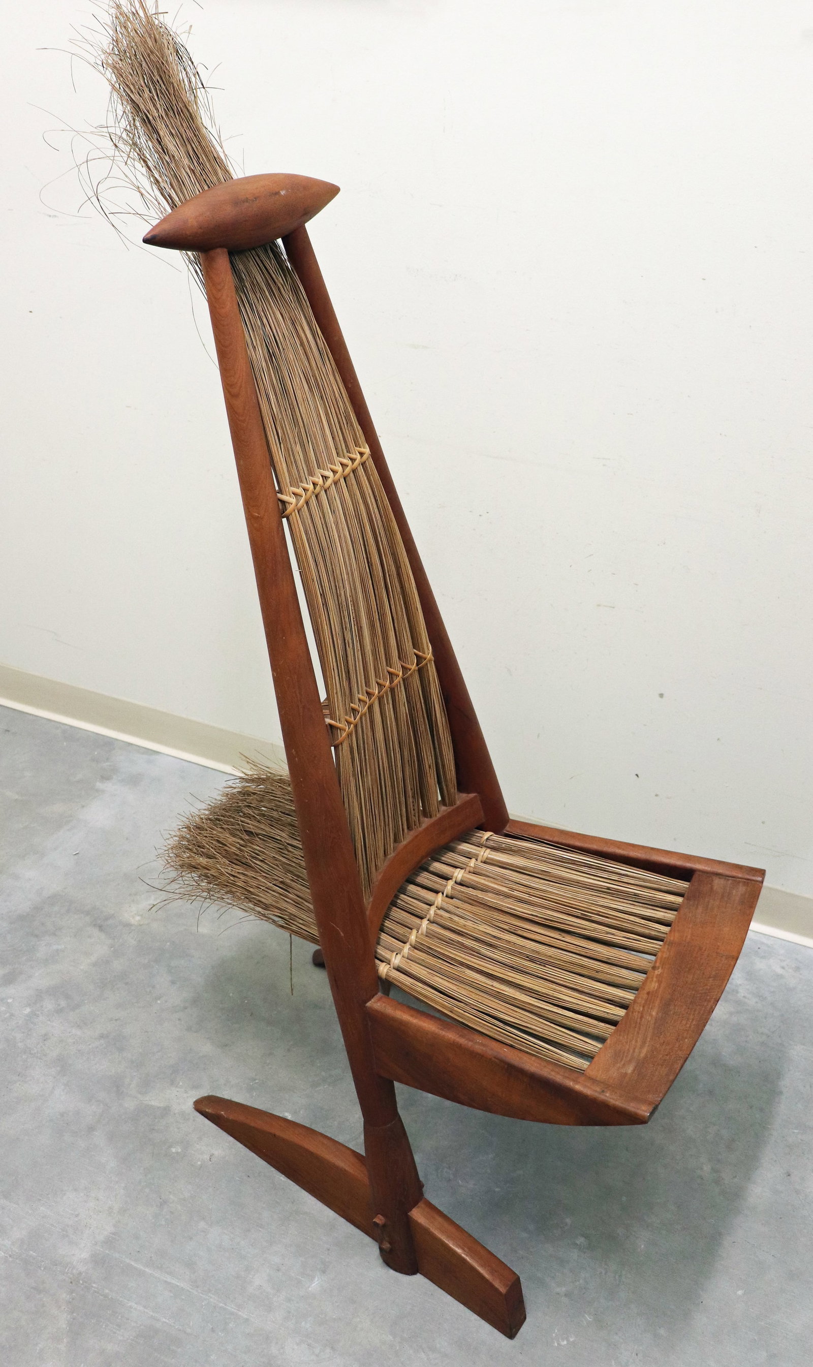 JOAQUIM TENREIRO STYLE SCULPTURAL CHAIR: Unusual mid century modern sculptural chair with a natural reed fiber seat and back in solid wood (teak ?). In the style of Joaquim Tenreiro. Including the reed extension it measures 59" H x 21.5"W x 