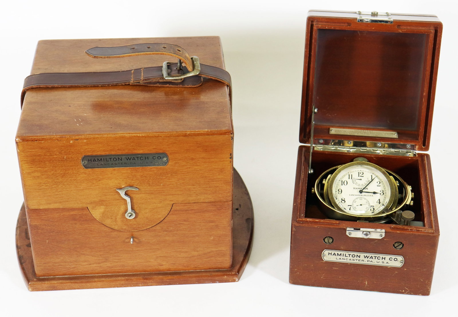 HAMILTON MODEL 22 CHRONOMETER IN BOX: Hamilton Model 22 cased chronometer watch. Chronometer is inside a wood and glass display case and includes additional wood box with leather straps. Both boxes with label on outside: Hamilton Watch Co