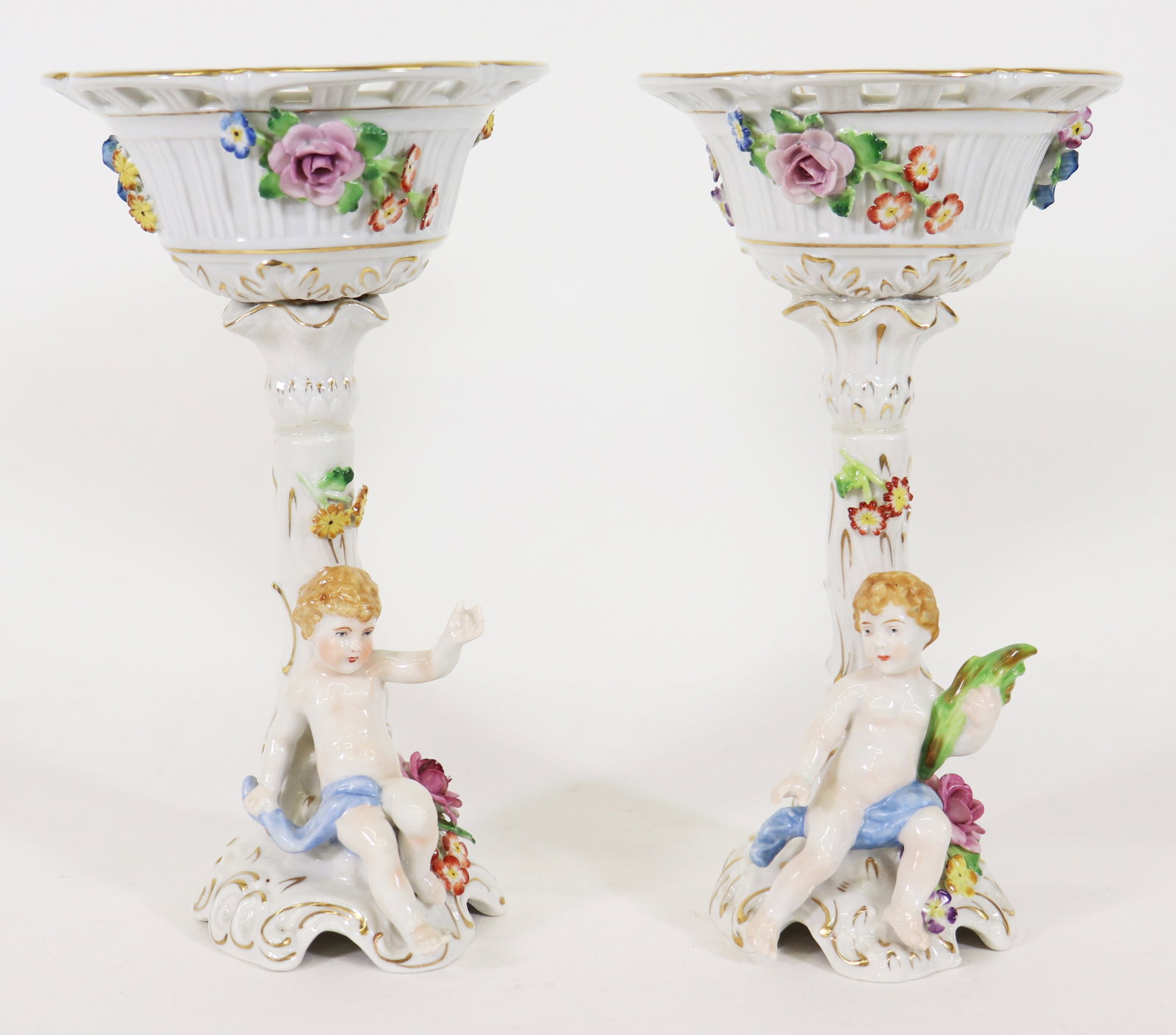 (2) GERMAN VON SCHIERHOLZ CHERUB COMPOTES: Pair of German porcelain figural footed compotes with cherub / putti and flowers. 9.5" tall 5.5" wide.