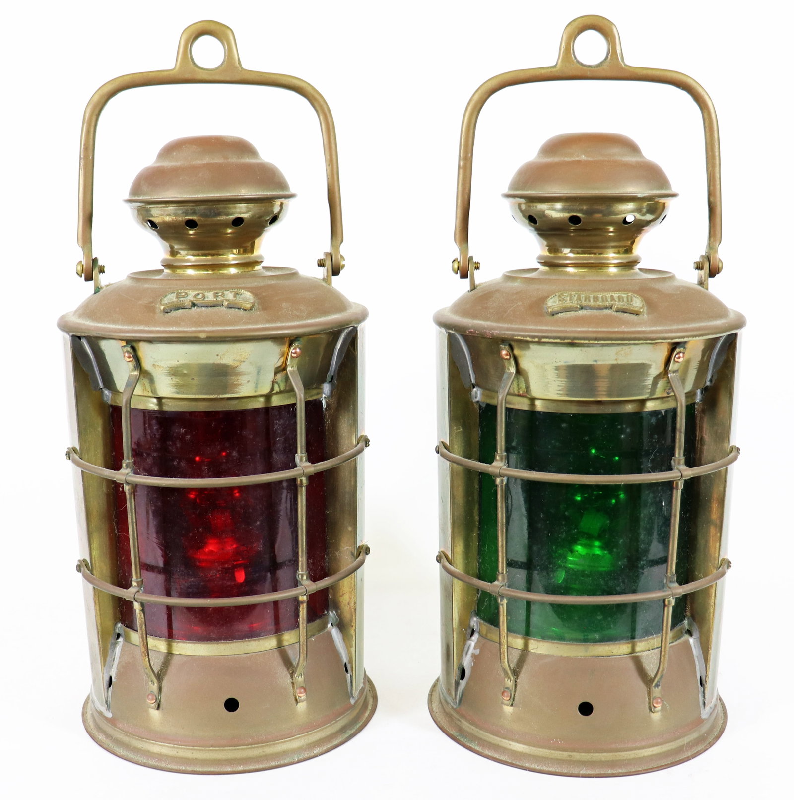 PAIR OF SHIP'S NAUTICAL NAVIGATION LANTERNS: A matched pair of marine navigation lanterns featuring red and green glass to indicate port and starboard positions on ships. Each has a ventilated cap, protective brass guard bars and handles for