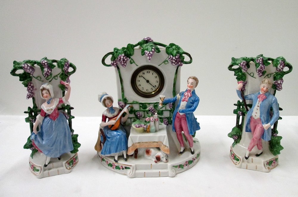 VINTAGE GERMAN PORCELAIN CLOCK & VASES: Three piece set with two vase garnitures and clock. Vases marked Germany 2804 8 1/4" tall, clock 9 1/2" tall 8 1/2" wide. Repair & damage to man's arm on clock.