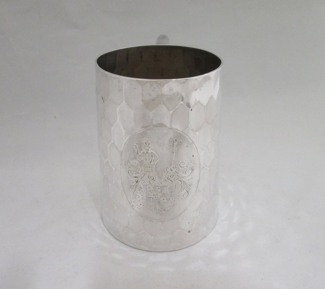 ANTIQUE HAMMERED GERMAN 800 SILVER MUG: 800 Silver hand hammered mug with German hallmarks on bottom - 800, half moon, crown, and unknown mark. Oval crest on mug has man with hammer, crest shield, and other designs. Some small dings on top 