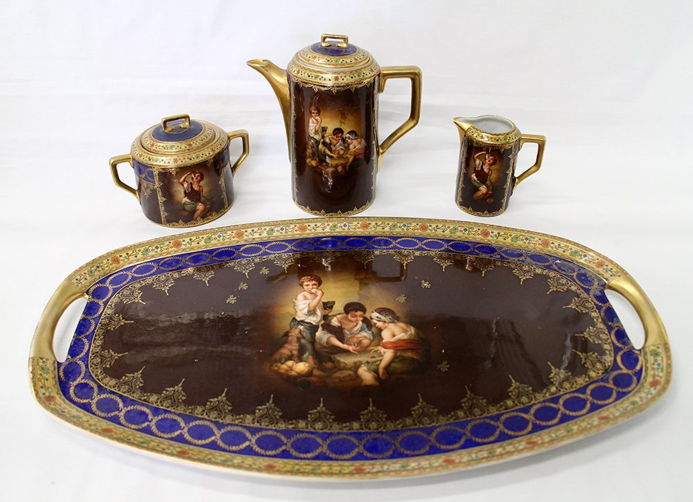 GERMAN PORCELAIN TEA SET: Four piece German Geschutzt tea set with blue beehive mark on bottom. Includes sugar, creamer, teapot, and tray (19 1/4" x 11").