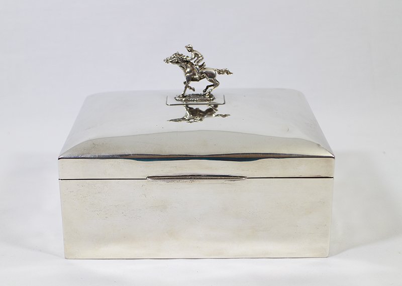 STERLING SILVER JOCKEY CIGAR HUMIDOR: Sterling silver humidor box with figural jockey on top. Hallmarks on box: Colen Cheshire maker, Chester England, & sterling. Jockey on lid with Italian hallmarks. Two indentations on lid. 7 1/8" x 5 5