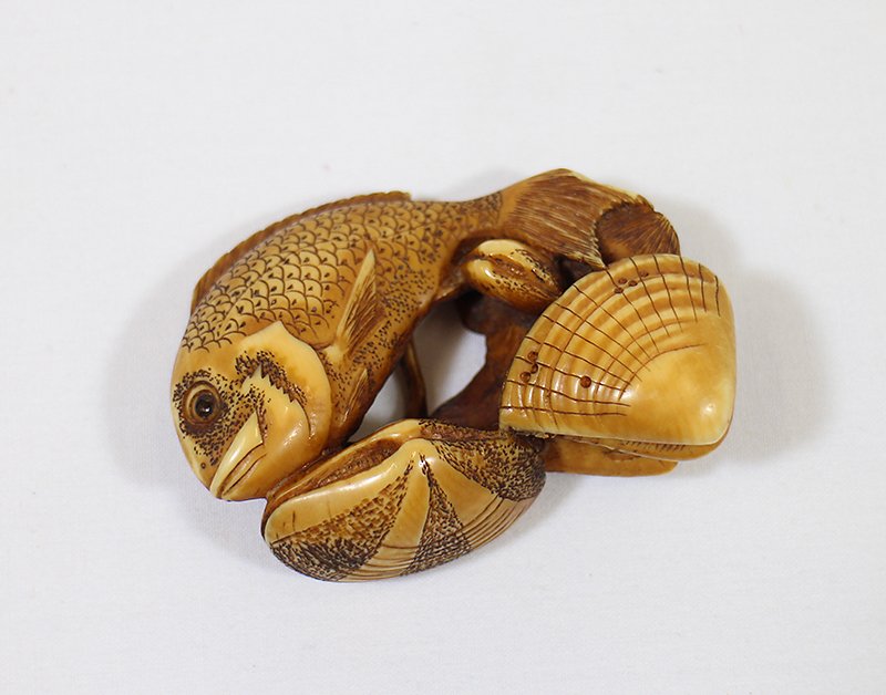 IVORY SEA LIFE CARVING: Figural ivory netsuke carving with sea life design (fish, clams, manta ray). Signed on bottom. 2 3/8" wide. Small chip to fish tail. THIS ITEM CANNOT BE SHIPPED OUT OF THE COUNTRY OR TO CALIFORNIA. PL