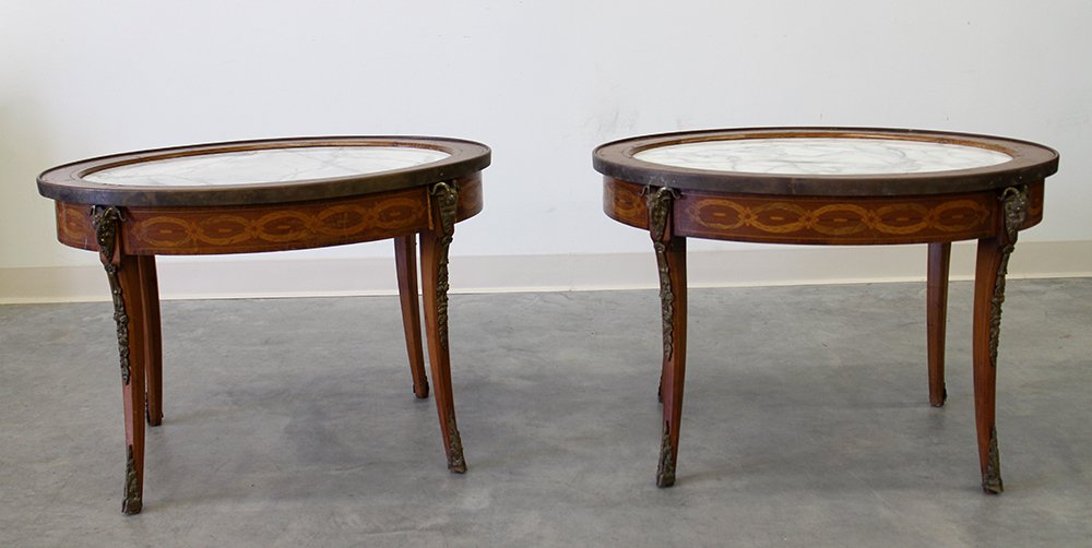 (2) FRENCH MARQUETRY INLAID TABLES W/ MARBLE: Pair of French marquetry tables with inlaid wood. Oval form with white marble inset, ormolu ram head & hoof accents. Small small areas of veneer loss. Tables measure 30 1/4" x 23" wide 20 3/4" tall.