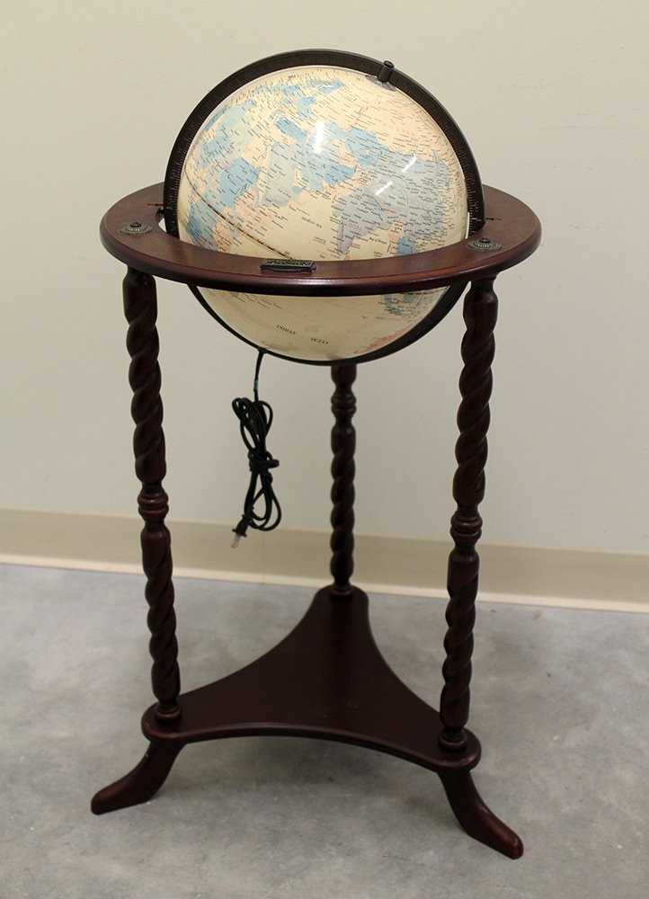 LIGHT UP WORLD GLOBE: Light up world globe lamp in a three leg wood stand. Label Thomas Pacconi 1900-2000 Classics. Approximately 35" tall.