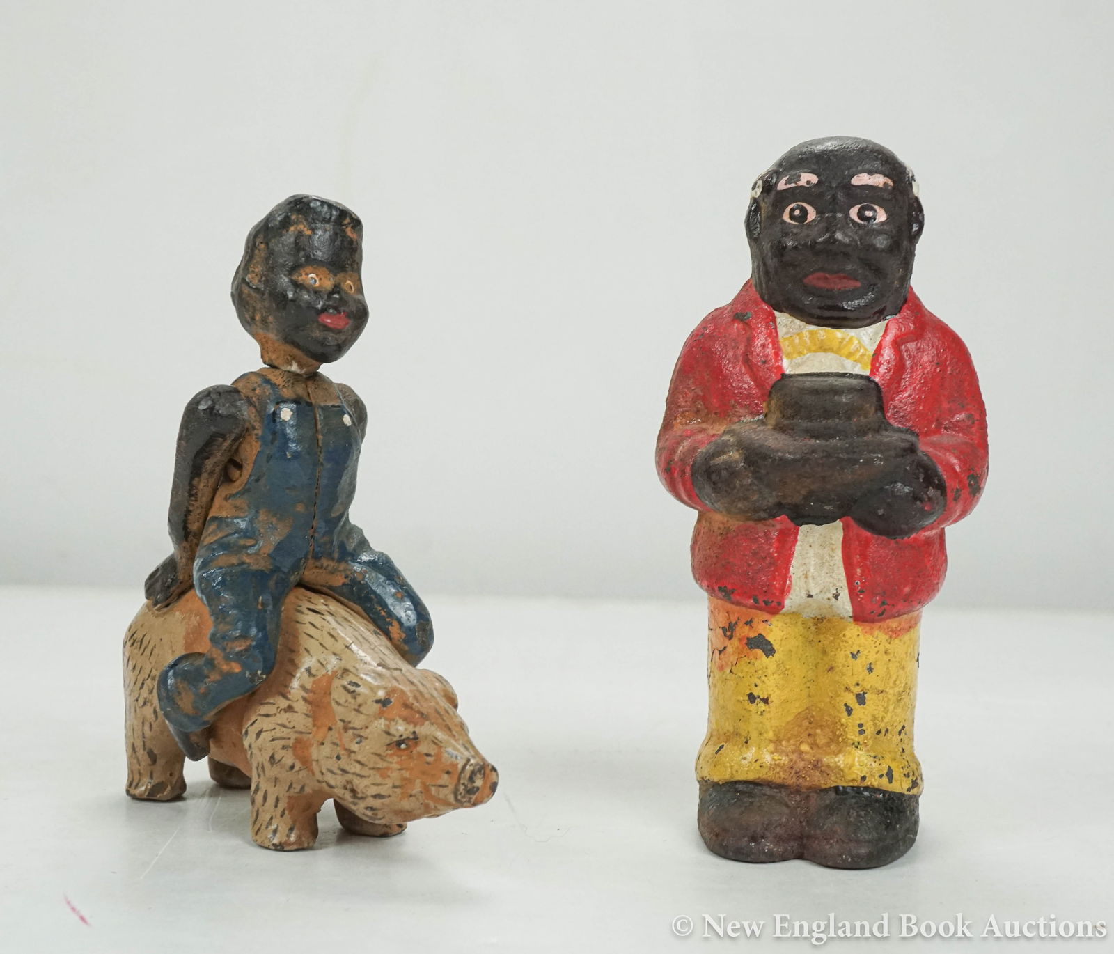 Cast Iron Banks: 35. Cast Iron Banks. Boy riding a pig * Black man holding his hat. 4-1/2 and 5 inches in height respectively, original paint (some chipping); generally sound. American, nd [200/300]