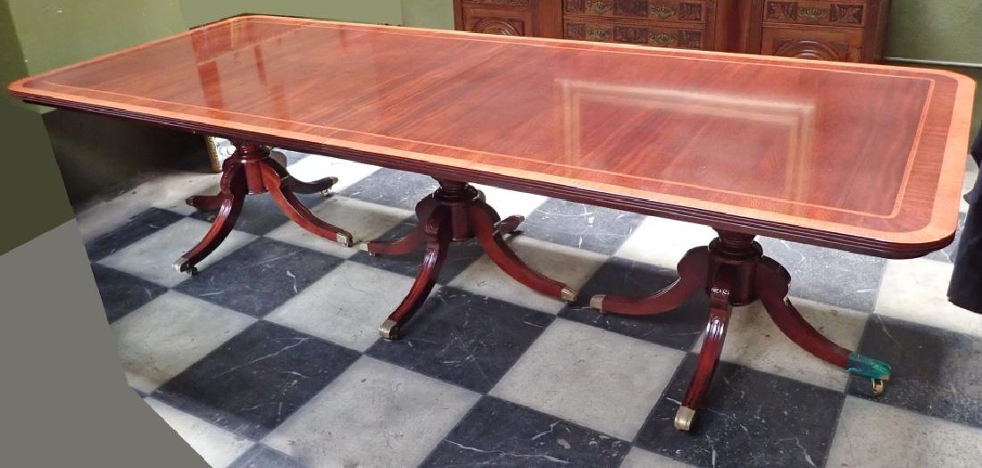 Banquet Size Triple Pedestal Mahogany Dining Table: Impressive crossbanded mahogany dining table features triple pedestals, 2 leaves and table pads. 20th Century Continental made. Sheraton style. Some surface wear, imperfections. Height: 30 1/2"; Width