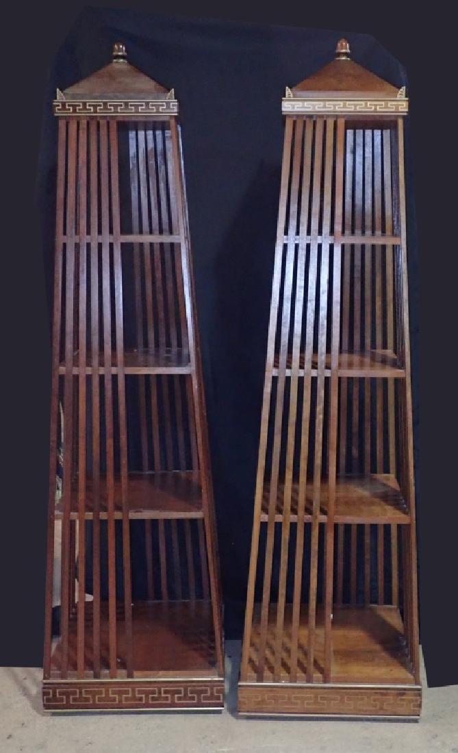 Pair Regency Style Obelisk Form Etageres: Set of two matching bookcases. Features swivel bases. Imperfections include two missing "ears", water stains, and one loose rung. Height: 75"; Width: 21"; Depth: 21". (Curio, display, bookcase, storag