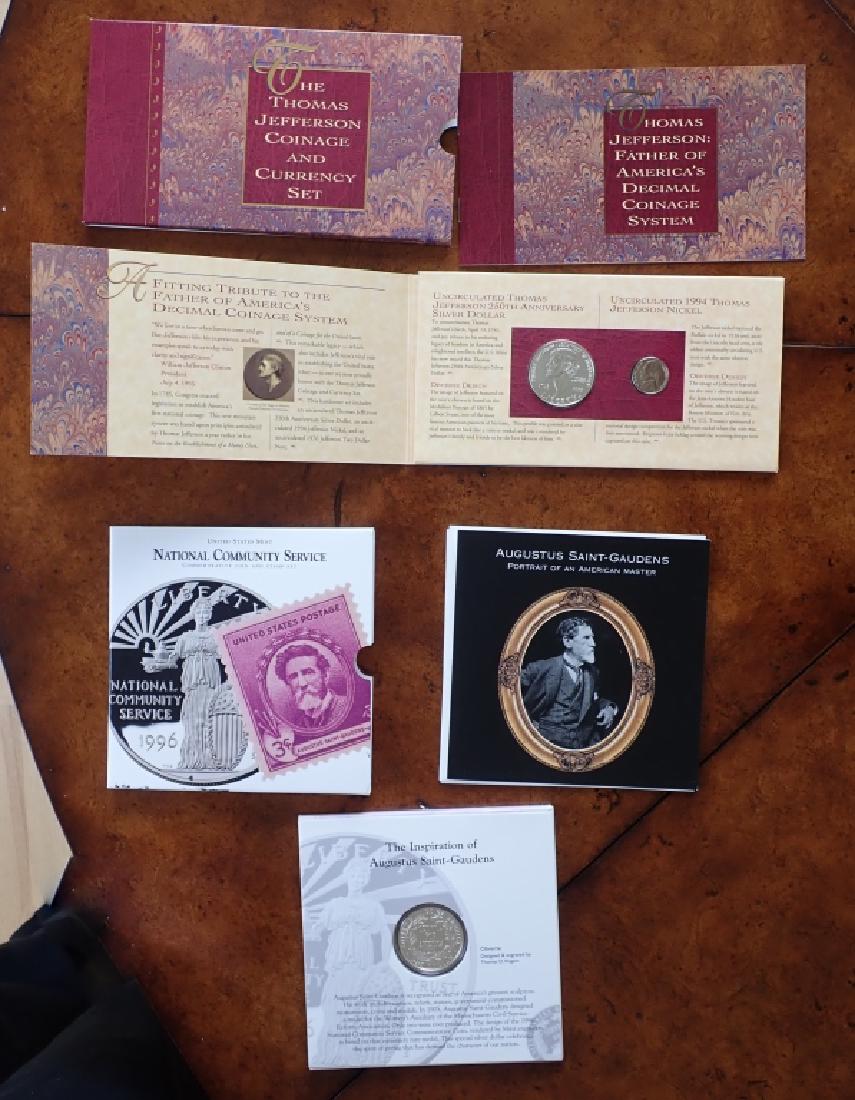 Two Commemorative Coin Sets: 2 sets include: - US Mint National Community Service Commemorative Coin and Stamp Set. Service for America one dollar coin, paperwork and sleeve. - The Thomas Jefferson Coinage and Currency Set. Uncir
