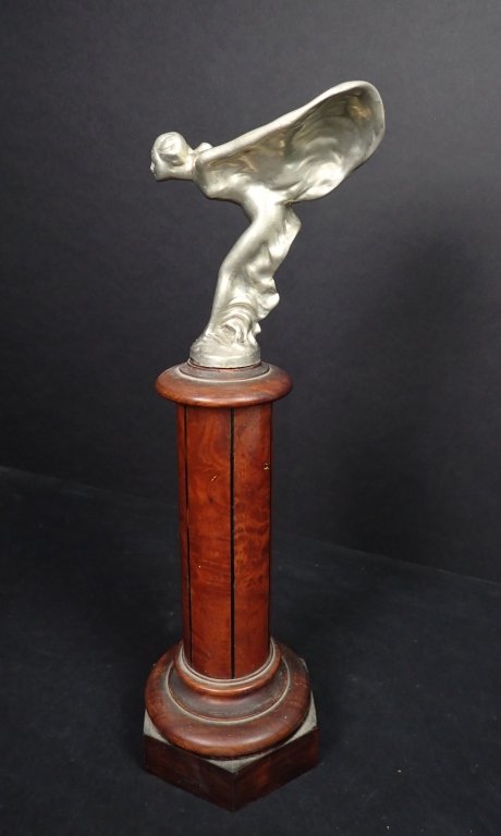 "Spirit of Ecstasy" Rolls Royce Hood Ornament: Rolls Royce "Flying Lady" Hood Ornament."Spirit of Ecstasy" after Charles Robinson Sykes (1875 - 1950) Mounted on a removable wooden base. Nickel or Silver over bronze. Marked Rolls Royce. Height of m