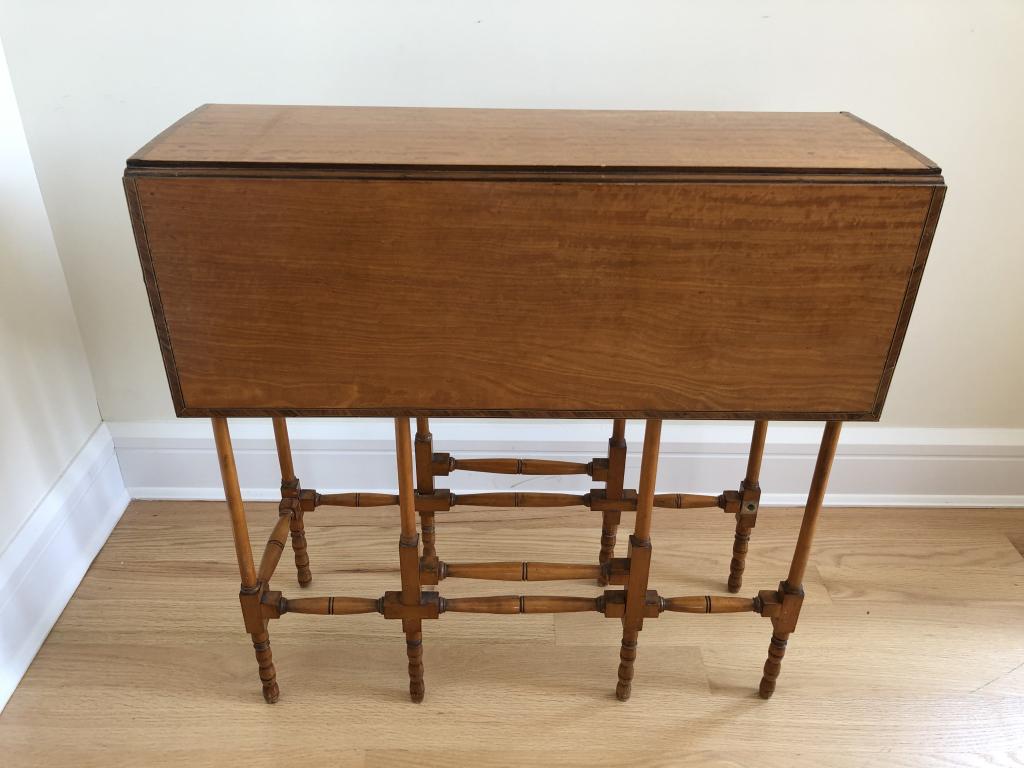 Folding Edwardian Satinwood Gate Leg Table: Vintage folding gate-leg side table. Imperfections include missing leg cross stretch / spindle post. Height: 27 3/4"; Width: 27 3/4"; Depth folded: 10"; Open: 28". STERLING ASSOCIATES STRIVES TO PROVI