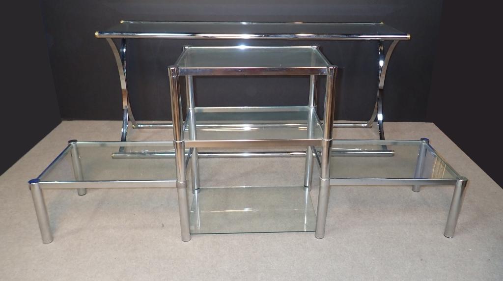 Modern Chrome & Glass Table Pairing: Two Clear glass top and chrome frame modern tables. Includes: Console table with crossed frame design. Height: 26"; Width: 60"; Depth: 19". Modular tiered coffee / side table with 5 shelves. Imperfect