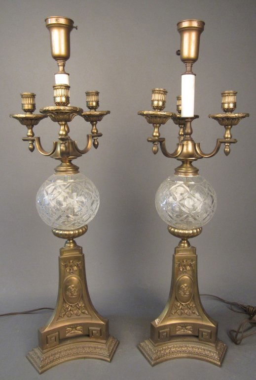 Pair Bronze and Cut Glass Candelabra as Lamps: Pair bronze and cut glass candelabra as lamps. 3 Candelabra arms with cut glass center. Base consists of putti and scrolling decoration design. circa 1910 Height: 32 3/8", Width: 10"