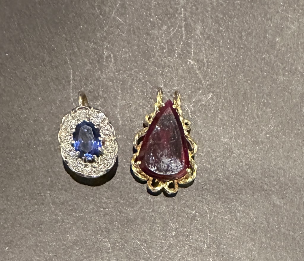 Two Gold Pendants 18k gold and garnet pendant along with a 14k gold diamond and blue stone pendant. (1 of 2)