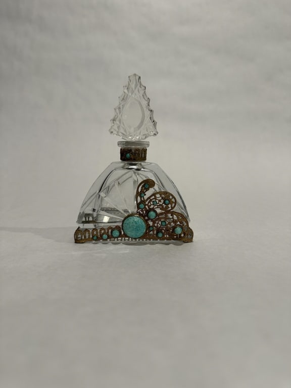Clear Glass Jeweled Perfume Bottle Art Deco brass and jewel mounted cut glass perfume bottle. Marked: Art Deco brass and jewel mounted cut glass perfume bottle. Marked Made in Cz. H. 5.75" STERLING ASSOCIATES STRIVES TO PROVIDE ACCURATE, OBJECTIVE, & FAIR INFORMATION ON ALL LOTS. WE WILL BE HAPPY TO A